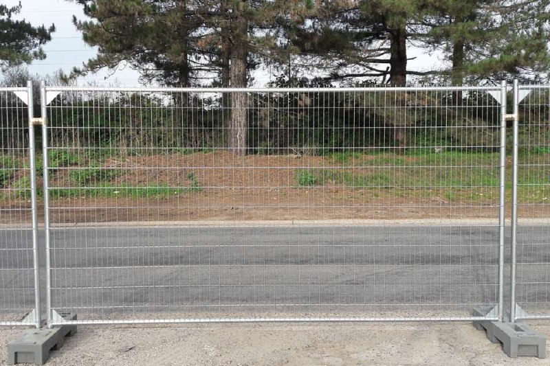 Temporary fence panels installed along a paved roadway on weighted bases